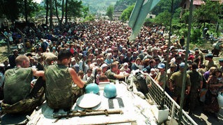 Niederländische UN-Friedenstruppen sitzen im Juli 1995 auf einem gepanzerten Transportfahrzeug, während sich muslimische Flüchtlinge aus Srebrenica in Ostbosnien im Dorf Potocari, etwa fünf Kilometer nördlich von Srebrenica, versammeln.