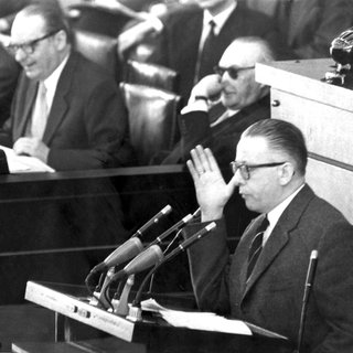 Der SPD-Abgeordnete Dr. Gustav Heinemann während der Debatte im Deutschen Bundestag in Bonn am 25.3.1958. Im Hintergrund Bundeskanzler Konrad Adenauer (mit Sonnenbrille), Außenminister Heinrich von Brentano (M) und Justizminister Fritz Schäffer. 