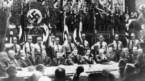 Leipzig, 11.11.1933: Bekenntnis der Professoren an den deutschen Universitäten zu Adolf Hitler. Auf dem Podium sitzend v. li., Schulrat Geyer, Stabsleiter des NSLB Sachsen (Glauchau); Rektor Prof. Dr. Golf (Leipzig); Rektor Prof. Dr. Eberhard Schmidt (Hamburg); Prof. Dr. Friedrich Karl Schumann (Halle); Prof. Dr. Emauel Hirsch (Göttingen); Gauobmann des NSLB Sachsen, Arthur Göpfert (Dresden); Rektor Prof. Dr. Martin Heidegger (Freiburg); Prof. Dr. Wilhelm Pinder (München); Rektor Prof. Dr. Eugen Fischer (Berlin) und Prof. Dr. Ferdinand Sauerbruch (Berlin)