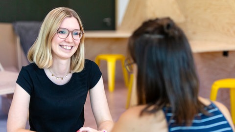 Zwei Frauen sitzen sich gegenüber und unterhalten sich