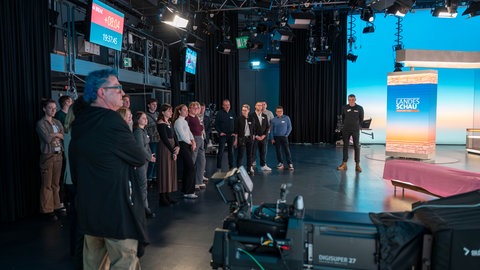 Das Bild zeigt eine Gruppe von Menschen, die an der Besucherführung im SWR teilgenommen haben. Sie stehen in einem Studio.
