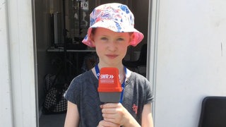 ARD Young Reporter Julia schaut sich beim SWR Sommerfestival 2023 in Ingelheim in der Maske um.