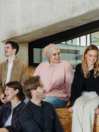 Eine Gruppe Menschen sitzt auf Stufen und interagiert.