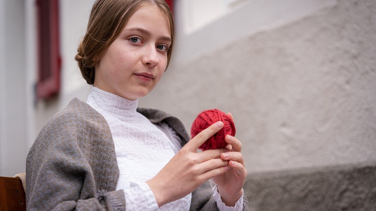 Martha Haberland als Margarete Steiff blickt ernst in die Kamera und hält einen Wollknäuel in der Hand.