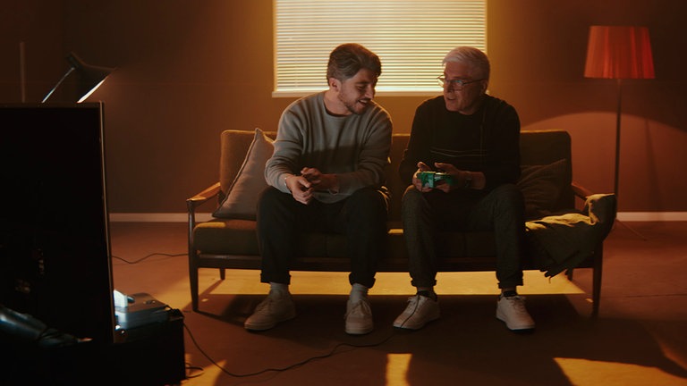 Khesrau (li.) zeigt seinem Vater, wie man Videospiele spielt