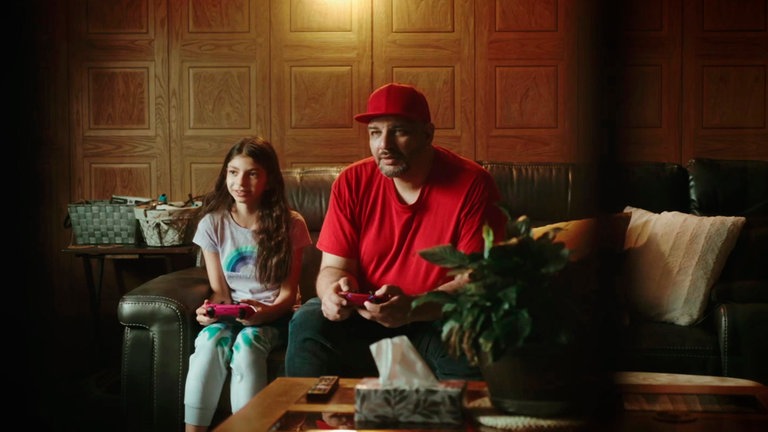 Osama (re.) spielt gemeinsam mit seiner Tochter ein Videospiel