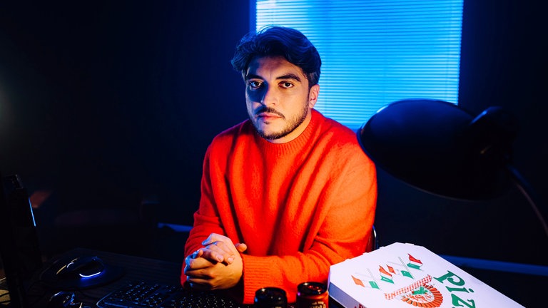 Khesrau Behroz sitzt an einem Schreitisch und schaut mit uns hinter die Kulissen der Gaming Industrie