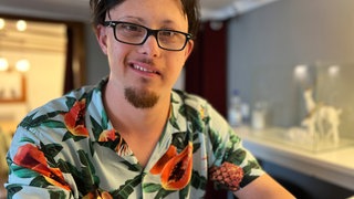 Jonas in einem bunten Blumenhemd mit offenem, verschmitztem Blick