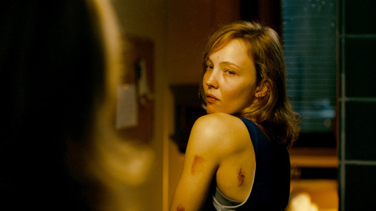 Rebecca (Magdalena Laubisch) schaut sich in einem Spiegel ihre Blessuren an