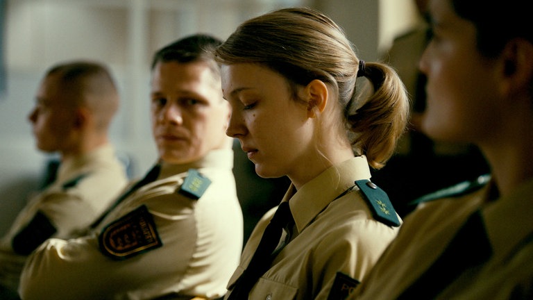 Rebecca (Magdalena Laubisch) sitzt neben einem Polizisten