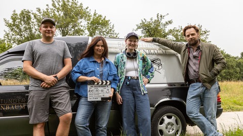 Regisseurin Lydia Bruna (2.v.r.) mit Hauptdarstellerin Anna Fischer, Hauptdarsteller Christoph Letkowski (rechts), Kameramann Clemens Majunke (links) und dem Leichenwagen der Firma Taubenbaum.