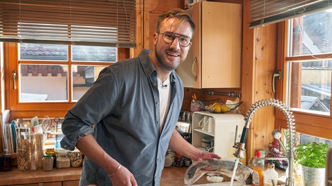 Sören Anders taut die Forelle auf, die er im Gefrierschrank gefunden hat. Daraus möchte er in zwei Stunden ein schmackhaftes Gericht für die ihm noch unbekannten Bewohner des Hauses zaubern. 