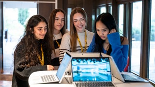 Vier Schülerinnen schauen auf einen Laptop