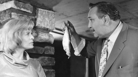 Gustav Knuth hält einen Fisch in der Hand und redet mit Renate Schacht.