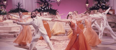 Das Ensemble des Tanzballetts tanzt in rosa Kulisse.