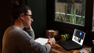 A young student works on a table near a pub window.  Close up view Alicante, Valencian Community, Spain 