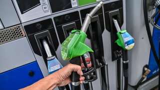 Eine Hand hält die Zapfpistole an einer Tankstelle. Eine Hand hält die Zapfpistole an einer Tankstelle. Auf dem Weg in den Urlaub mit dem Auto lässt sich mit dem richtigen Tankstopp viel Geld sparen. Wir klären, wohin man günstiger vollgetankt fährt und wo sich Tanken im Ausland lohnt.