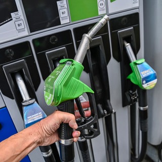 Eine Hand hält die Zapfpistole an einer Tankstelle. Eine Hand hält die Zapfpistole an einer Tankstelle. Auf dem Weg in den Urlaub mit dem Auto lässt sich mit dem richtigen Tankstopp viel Geld sparen. Wir klären, wohin man günstiger vollgetankt fährt und wo sich Tanken im Ausland lohnt.