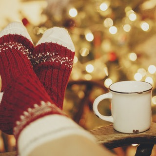 Gemütlich hochgelegte Füßen in Wollsocken und eine Tasse Tee