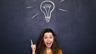 Frau zeigt auf eine gezeichnete Glühbirne
