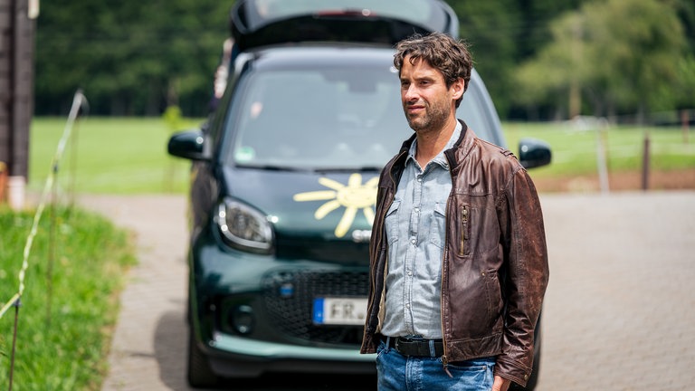 Lars (Kai Albrecht) steht nachdenklich vor seinem kleinen Auto