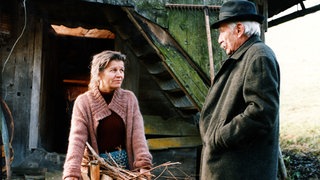 Lioba trägt einen Korb mit Holz und spricht mit Wilhelm