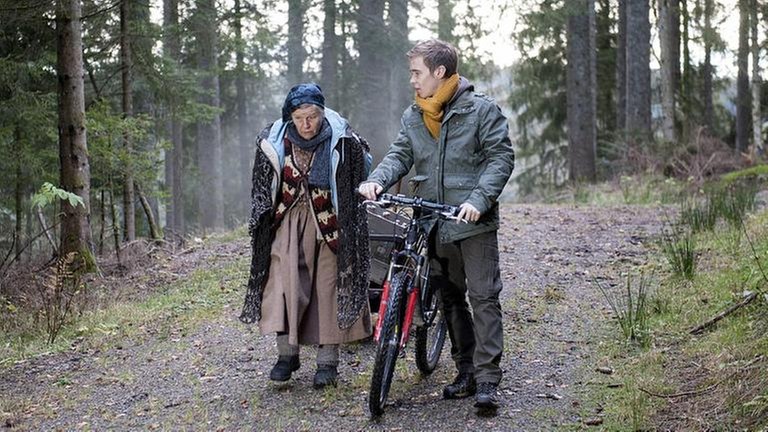 Lioba ist mit Sebastian, der sein Fahrrad schiebt, im Wald unterwegs