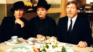 Marias Angehörige sitzen in Trauerkleidung beim Leichenschmaus