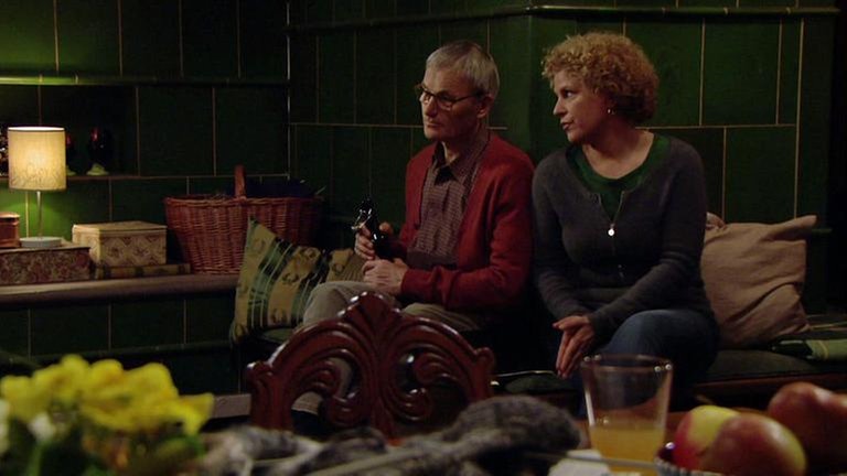 Folge 1041 - Bea und Karl sitzen am Kachelofen im Wohnzimmer