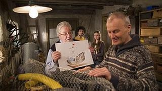 Karl arbeitet im Brunnengang, Hermann zeigt ihm ein Bild, im Hintergrund stehen Albert und Lena