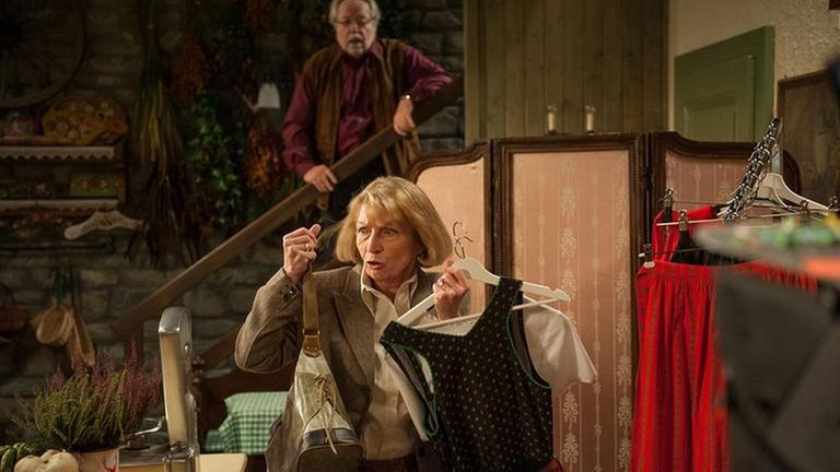 Maria verlässt fluchtartig den Hofladen, im Hintergrund steht Hermann auf der Treppe