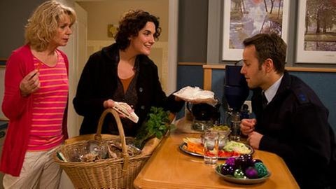 Monique hat Murat etwas zu essen mitgebracht, Kati steht beobachtend hinter Monique
