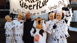 Die Milchjoggele halten ein Banner hoch, Wilhelm steht in deren Mitte