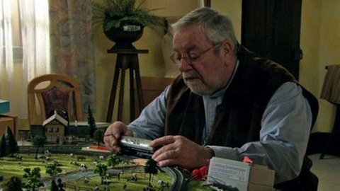 Hermann spielt mit seiner Modelleisenbahn