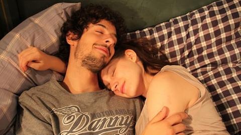 Albert und Celine liegen aneinandergekuschelt im Bett
