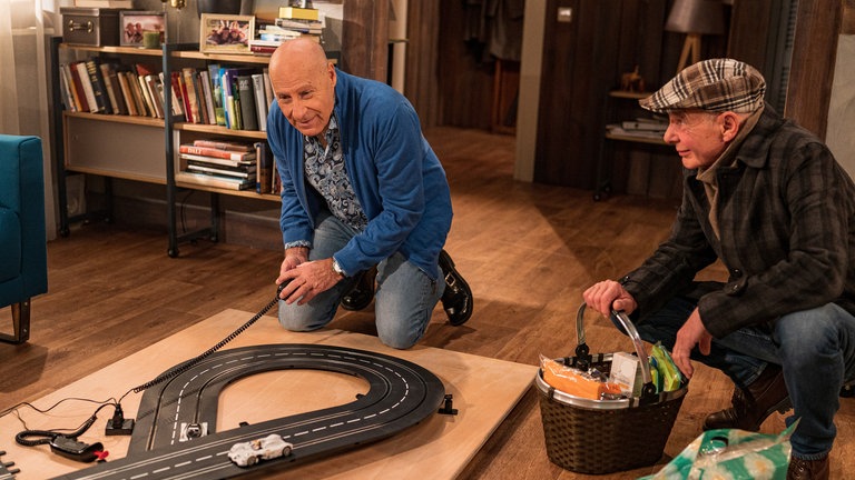 Franz und Heinz sitzen auf dem Boden und spielen mit einer Eisenbahn