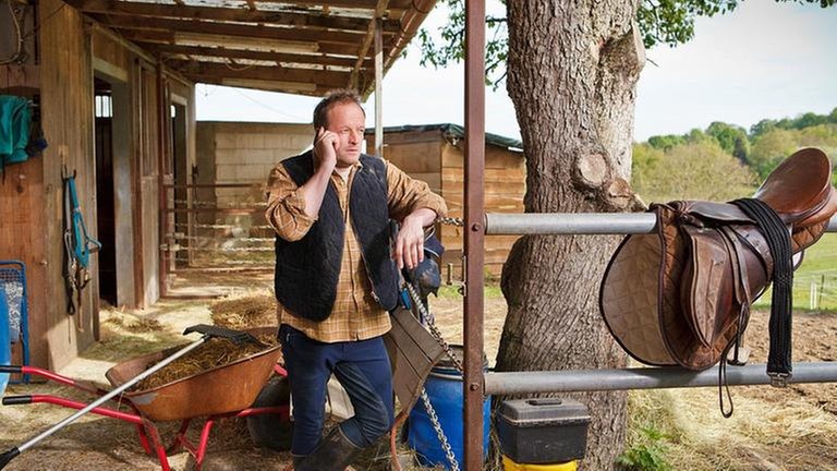 Bernd steht vor dem Gestüt und telefoniert