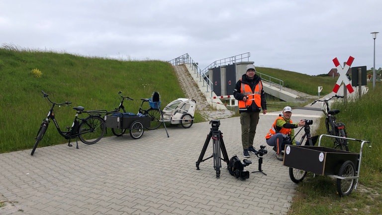 „Greenproduction“ – „autofrei“ gilt auf Wangerooge auch für das Eisenbahn-Romantik Team. Für die Dreharbeiten mussten Fahrräder mit Hänger gemietet werden. Tonmann Wolfgang Steiner und Kameramann Andreas Enderle, knieend, bei der Vorbereitung einer Aufnahme.