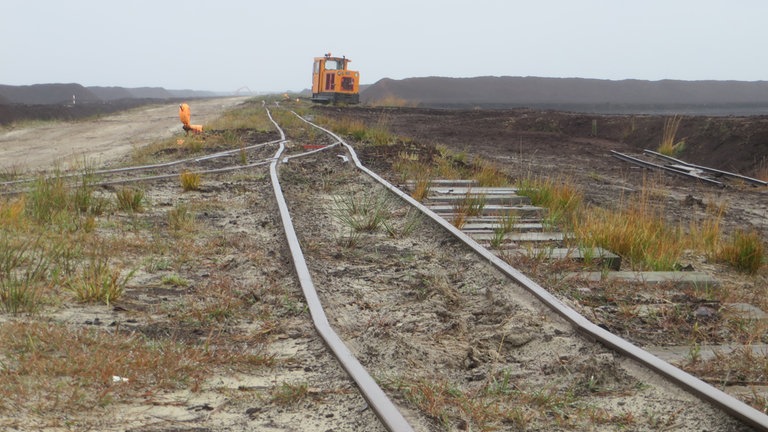Links und rechts der Gleise warten Kilometer lange Torfmieten auf ihren Abtransport