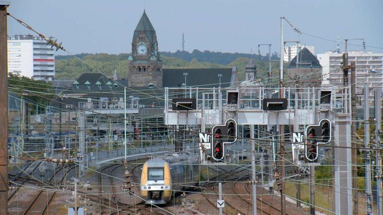 Die südliche Einfahrt in den Bahnhof Metz-Ville. Im Hintergrund sichtbar der Uhrenturm am Bahnhofsgebäude, sowie der Wasserturm, der für die Versorgung der Dampflokomotiven mit Wasser zuständig war.