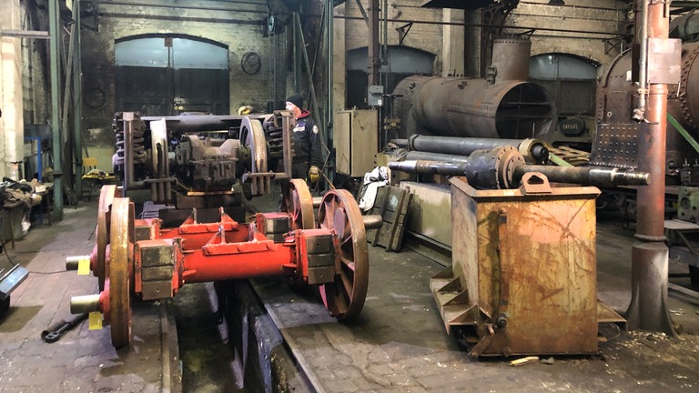 Die Drehgestelle werden in der MaLoWa Bahnwerkstatt zerlegt. Die Achsen sollen durch Pressen auf die karibische Spurweite von 750 mm gebracht werden. 