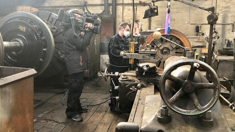 Dreharbeiten 2021 beim Ausschleifen von neuen Radreifen. Nachdem die Presse beim Versuch, die Achsen auf Maß zu bringen, kaputt gegangen ist, soll nun so die Spurweite angepasst werden. 