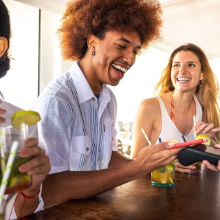 Mann bezahlt in Strandbar mit dem Handy