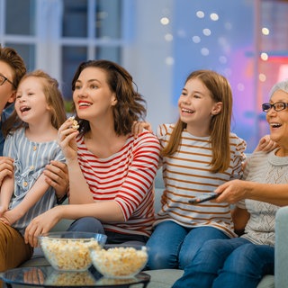 Familie sitzt auf der Couch und schaut fern