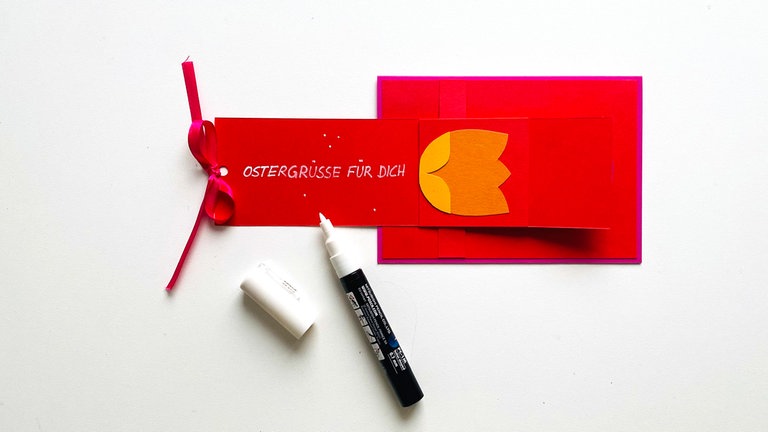 Den Mechanismus ganz aufziehen, das Band durch das Loch fädeln und eine Schleife machen. Nun kann ein Text auf den "Zieher" geschrieben werden.