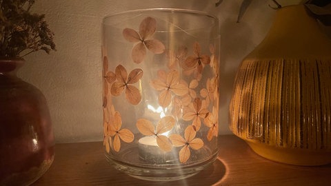 Die laminierte Folie dient nun als Manschette für eine Vase oder ein Glas. Die Breite oder Höhe der Folie kann mit der Schere angepasst werden. Die Manschette am Schluss mit etwas transparentem Klebefilm verschließen. 