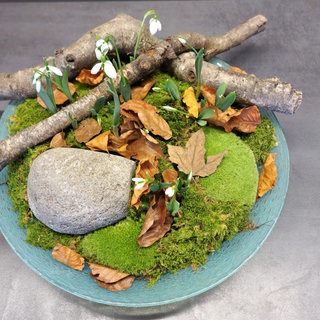 Winterliche Dekoration mit Schneeglöckchen, Moos, Ästen und Zweigen