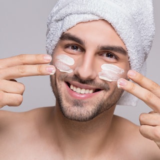 Mann cremt sich das Gesicht ein