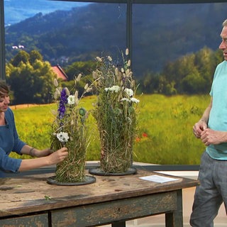 Floristmeisterin Jasmin Centner gestaltet eine Kugel aus trockenem Material mit Gras und Sommerblumen dekoriert