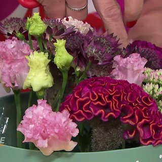 Eine Floristin steckt Blumen in eine Geschenkbox